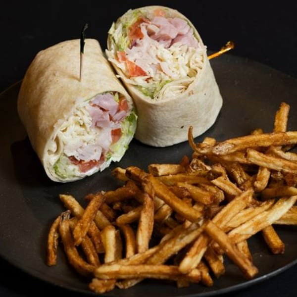 Two ham and cheese wraps with lettuce and tomato, served with a side of golden french fries.